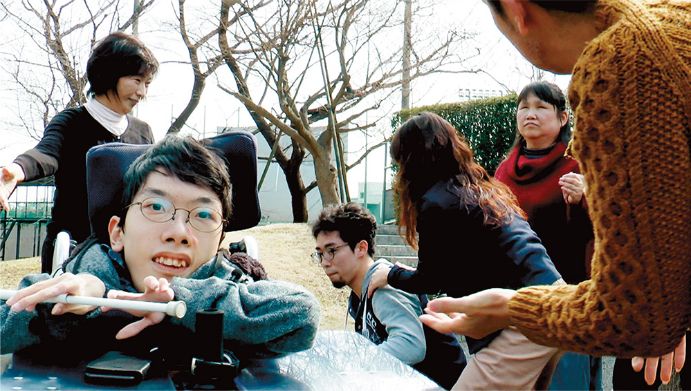 車椅子の石田監督の後ろでパフォーマンスする出演者たち